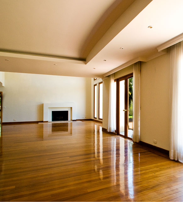A spacious, empty room featuring a polished hardwood floor, showcasing the aftermath of cutting-edge demolition work.