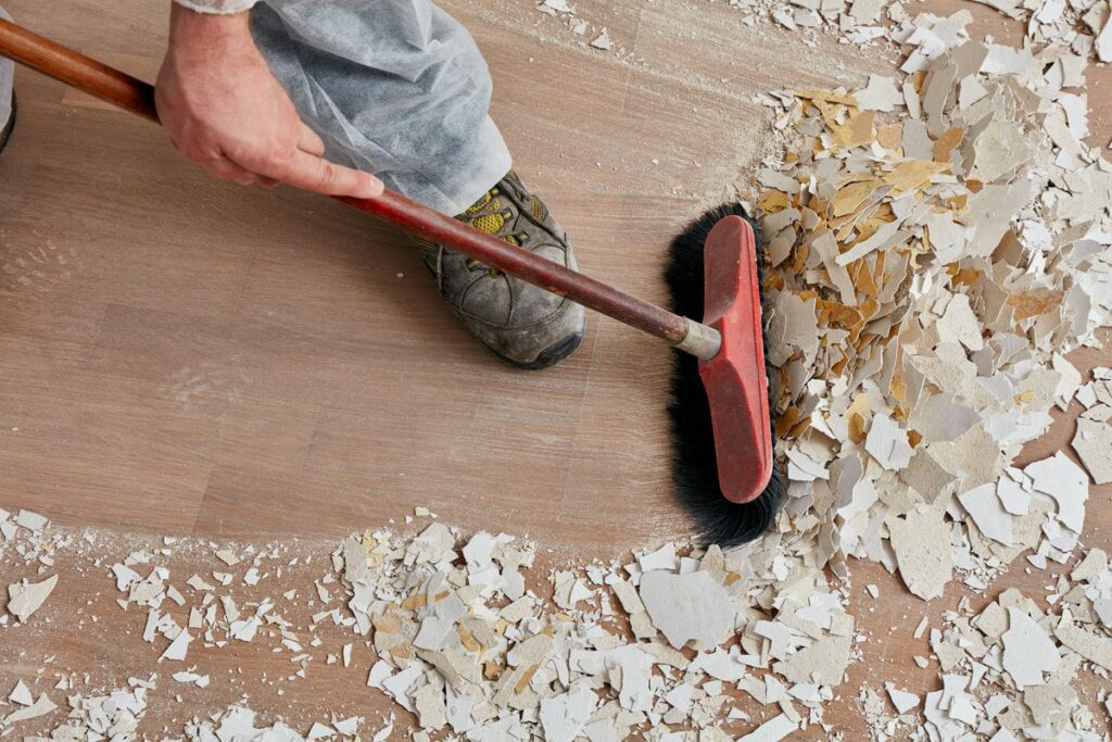 A man is using a broom to clean the floor, demonstrating attention to cleanliness and order.