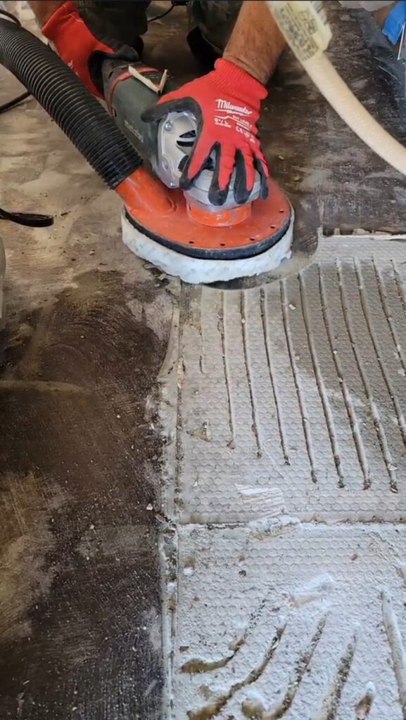 A man is engaged in grinding concrete with a power grinder, demonstrating expertise in construction work.