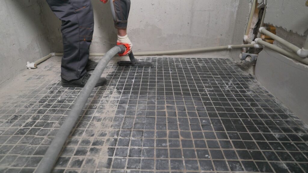 Worker vacuuming a tiled floor in a construction site.