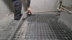 Worker vacuuming a tiled floor in a construction site.