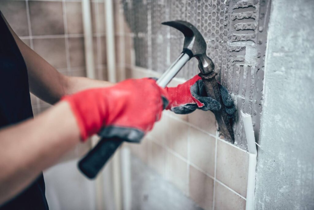 A hand in a red glove grips a hammer indicating preparation for a construction or repair activity