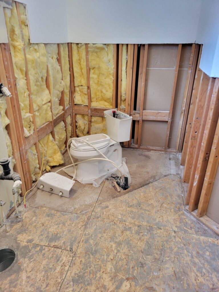 A clean bathroom featuring a toilet and a shower with neutral colored tiles and bright lighting