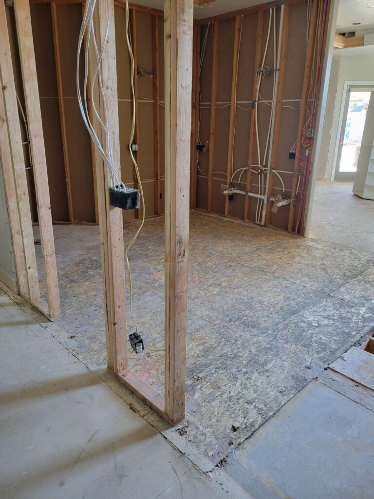 Interior view of a room with a wooden frame and a damaged wall that has a significant hole in it