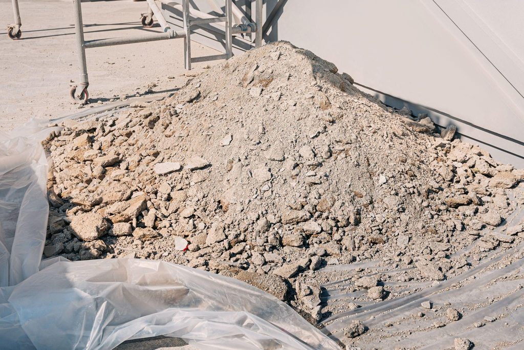 A pile of dirt resting on a blue tarp showcasing the texture and color of the soil against the fabric